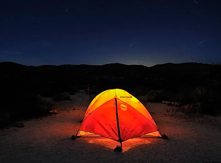 Tenda illuminata di arancione di notte in un campeggio